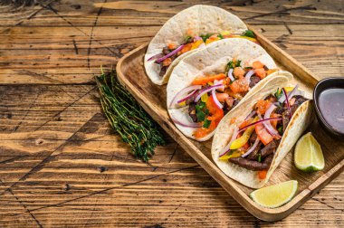 Biftek, soğan, domates, tatlı biber ve salsa soslu taco. Meksika yemeği. Ahşap arka plan. Üst Manzara. Boşluğu kopyala