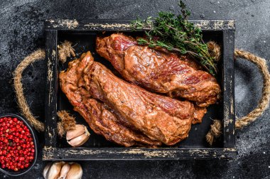 Tahta tepside salamura edilmiş biftekler ve şifalı otlar. Siyah arka plan. Üst görünüm