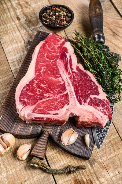 Roh Porterhouse oder T-bone beef meat Steak mit Kräutern auf einem hölzernen Schneidebrett. Holzuntergrund. Ansicht von oben — Stockfoto