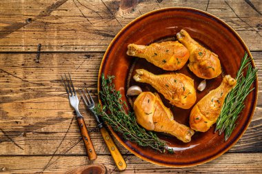 Kırsal bir tabakta taze tütsülenmiş tavuk budu ve otlar. Ahşap arka plan. Üst Manzara. Boşluğu kopyala