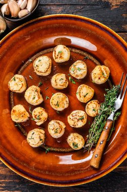 Tabakta tereyağlı baharat soslu kızarmış istiridye. Koyu ahşap arka plan. Üst görünüm