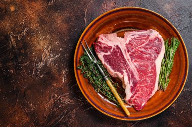 Çiğ biftek bifteği ve tabakta otlar. Karanlık arka plan. Üst Manzara. Boşluğu kopyala