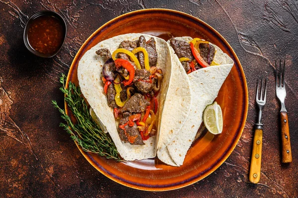 Fajitas Tortilla wraps with beef meat steak stripes, sweet pepper and onions. Dark Wooden background. Top view — Stock Photo, Image