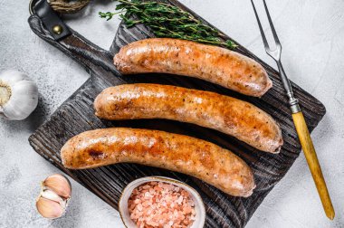 Ahşap kesme tahtasının üzerinde baharat ve otlarla kızartılmış sosisler. Üst Manzara. Beyaz arkaplan