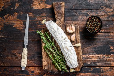 İspanyol kurutulmuş salçalı salamı kesme tahtasında. Koyu ahşap arka plan. Üst görünüm