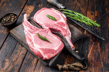 Mermer, çiğ domuz pirzolası, biftek ya da balta. Koyu ahşap arka plan. Üst görünüm