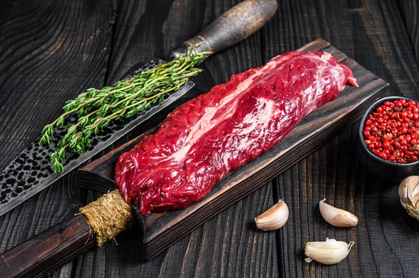 Raw Onglet Hanging Steak de viande de bœuf tendre sur une planche à découper en bois. Fond en bois noir. Vue du dessus — Photo