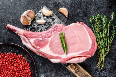 Et satırında çiğ balta domuz pirzolası biftek. Siyah arka plan. Üst görünüm