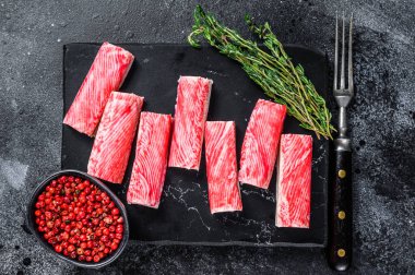 Yengeç surimi mermer tahtaya yapışıyor. Siyah arka plan. Üst görünüm