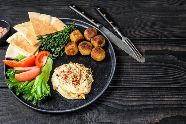 Arabská kuchyně Cizrna Hummus, falafel, chléb pita a čerstvá zelenina. Černé dřevěné pozadí. Horní pohled. Kopírovat prostor — Stock fotografie