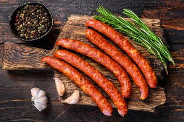 Taze aromatik otlar ve baharatlarla birlikte sıcak füme sosis. Koyu ahşap arka plan. Üst görünüm