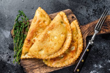 Et ve bitkilerle yağlı cheburekler içinde kızartılmış, geleneksel Kafkas mutfağı. Siyah arka plan. Üst görünüm