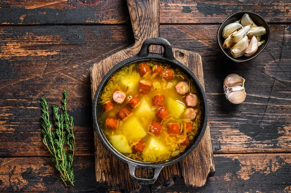 Split pea soup with smoked sausages in a pan. Dark wooden background. Top view — Stock Photo, Image