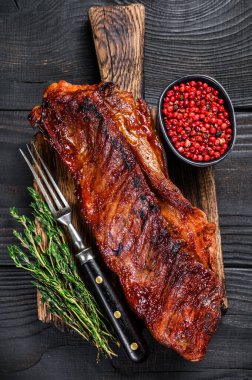 bbq soslu dana etinde ızgara. Tahta kesme tahtasının üzerinde kaburga eti. Siyah ahşap arka plan. Üst görünüm