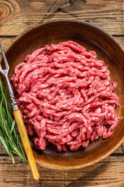 Çiğ kıymalı kuzu eti, tabakta otlu kuzu eti. Ahşap arka plan. Üst görünüm