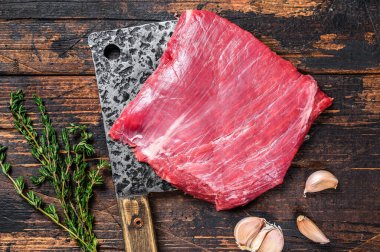 Çiğ etek, satırda mermer biftek. Karanlık ahşap arka plan. Üst görünüm