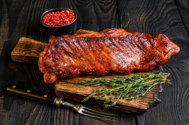 bbq soslu dana etinde ızgara. Tahta kesme tahtasının üzerinde kaburga eti. Siyah ahşap arka plan. Üst görünüm