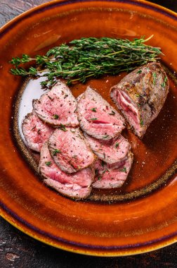 Tabakta ızgara ve dilimlenmiş kuzu fileto biftek. Karanlık arka plan. Üst görünüm