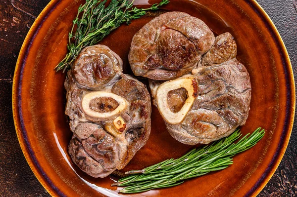 Carne cocida en el hueso vástago de ternera Osso Buco, filete de ossobuco italiano. Fondo de madera oscura. Vista superior —  Fotos de Stock