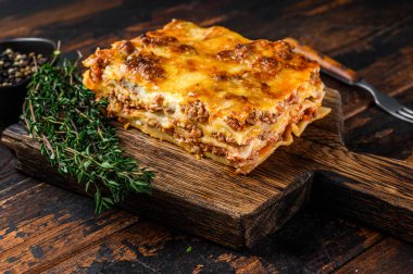 Bolonez soslu ve kıymalı İtalyan lazanyası. Karanlık ahşap arka plan. Üst görünüm