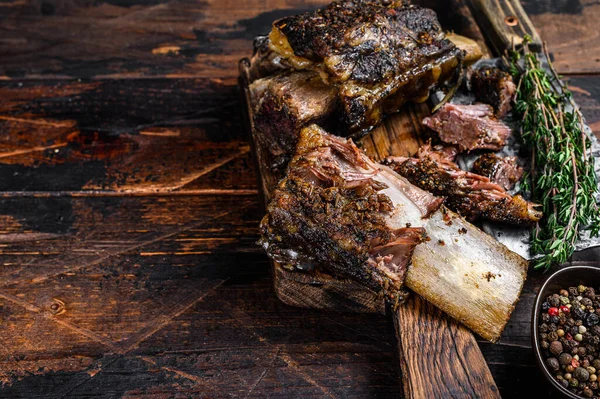 BBQ short chuck beef ribs with herbs and meat cleaver. Dark wooden background. Top view. Copy space