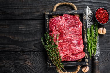 Çiğ et eti. Tahta tepside otlarla kesilmiş et. Siyah ahşap arka plan. Üst Manzara. Boşluğu kopyala