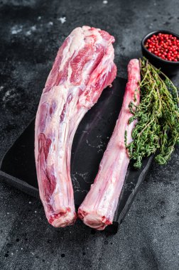 Taze çiğ sığır eti, öküz kuyruğu eti mermer tahtada otlarla birlikte. Siyah arka plan. Üst görünüm