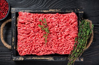 Çiğ kıyma ve ahşap tepside otlu domuz eti. Siyah arka plan. Üst görünüm