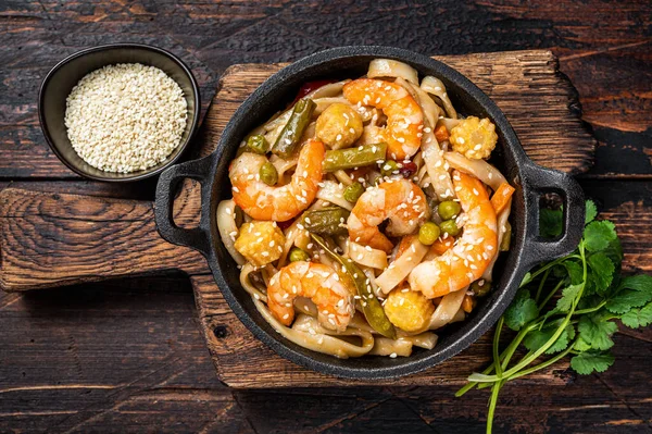 Aziatische Udon roerbak noedels met garnalen in een pan. Donker houten achtergrond. Bovenaanzicht — Stockfoto