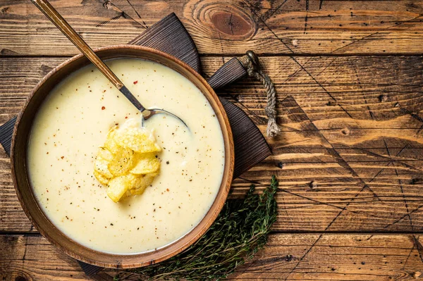 Cream potato soup with potato chips in wooden plate. wooden background. Top view. Copy space