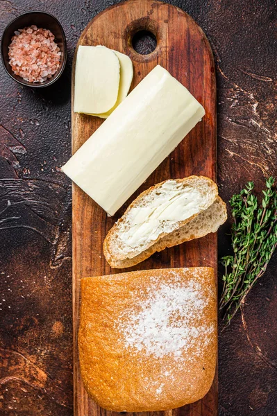 Sliced toast bread with butter spread on a wooden cutting board. Dark background. Top view — Stock Photo, Image