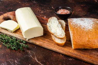 Tahta kesme tahtasına tereyağlı dilimlenmiş tost ekmeği. Karanlık arka plan. Üst görünüm