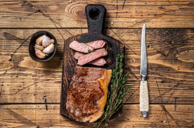 Dilimlenmiş ızgara New York bifteği ya da ahşap bir tahtanın üzerinde striploin. Ahşap arka plan. Üst görünüm