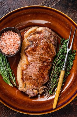 Kızarmış New York bifteği ya da kırsal bir tabakta striploin. Karanlık arka plan. Üst görünüm