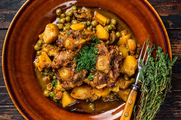 Lammragout mit Gemüse in einem rustikalen Teller. Dunkler Holzhintergrund. Ansicht von oben — Stockfoto