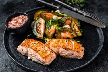 Kızarmış somon fileto biftekli ve roka salatalı balık yemeği. Siyah arka plan. Üst görünüm