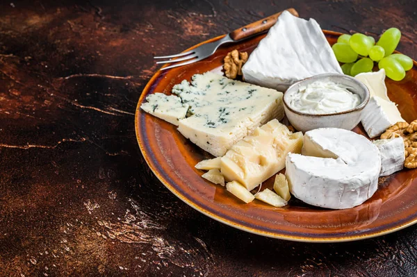 Prato de queijo com Brie, Camembert, Roquefort, queijo creme azul, uva e nozes. Fundo escuro. Vista superior. Espaço de cópia — Fotografia de Stock