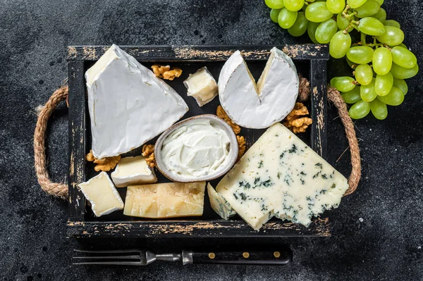 Prato de queijo variado com Brie, Camembert, Roquefort, parmesão, queijo creme azul, uva e nozes. Fundo preto. Vista superior — Fotografia de Stock