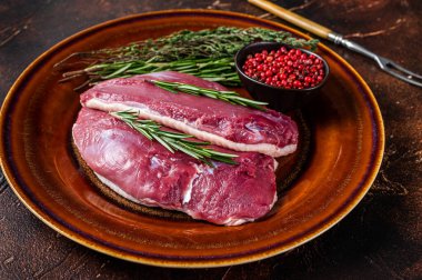 Köy tabağında çiğ göğüs bifteği ve biberiye. Karanlık arka plan. Üst Görünüm