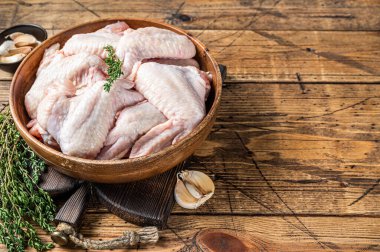 Tahta bir tabakta çiğ tavuk kanadı kekik ve sarımsaklı. Ahşap arka plan. Üst Manzara. Boşluğu kopyala