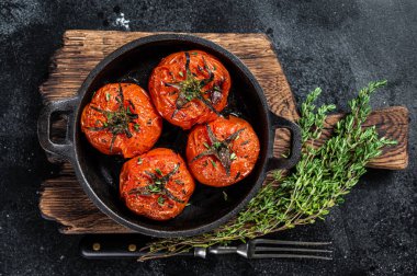 Tavada kekik olan kızarmış kiraz domatesleri. Siyah arka plan. Üst görünüm