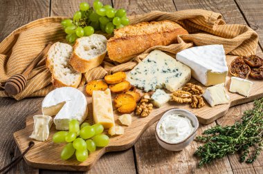 Peynirli peynirli, peynirli, peynirli, rokforlu, parmesanlı, üzümlü, incirli, ekmekli ve fındıklı krem peynirli. Ahşap arka plan. Üst görünüm