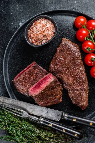 Pečený hovězí steak z denveru na talíři s tymiánem. Černé pozadí. Horní pohled — Stock fotografie