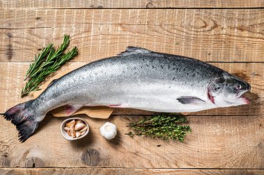 Tahta bir kichen masasında otlarla birlikte çiğ somon balığı. Ahşap arka plan. Üst görünüm