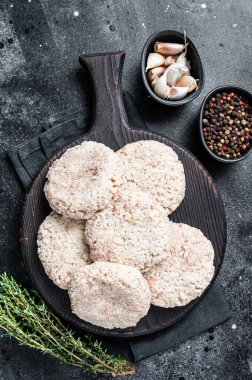 Pişmemiş çiğ köfte pirzolası ahşap kesme tahtasının üzerinde otlarla birlikte. Siyah arka plan. Üst görünüm