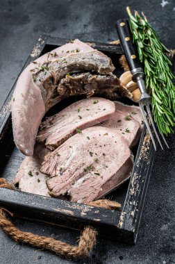 Pişmiş dana eti ya da ahşap bir tepside dilimlenmiş sığır dili. Siyah arka plan. Üst görünüm