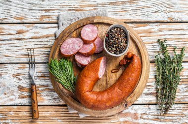 Bavyera füme sosisi ahşap bir tahtanın üzerinde otlarla birlikte. Beyaz ahşap arka plan. Üst görünüm