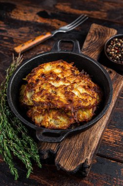 Kızarmış patates gözlemesi ya da tavada otlu börek. Koyu ahşap arka plan. Üst görünüm