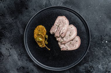 Bir tabakta haşlanmış dil dilimleri. Siyah arka plan. Üst görünüm