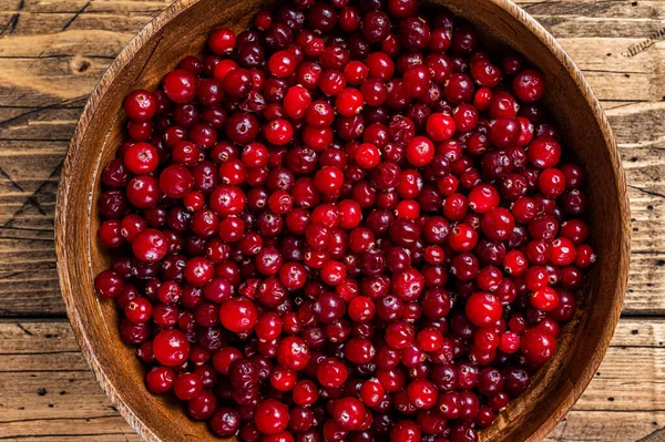 Rode Cranberry bes in een houten bord. Houten achtergrond. Bovenaanzicht — Stockfoto